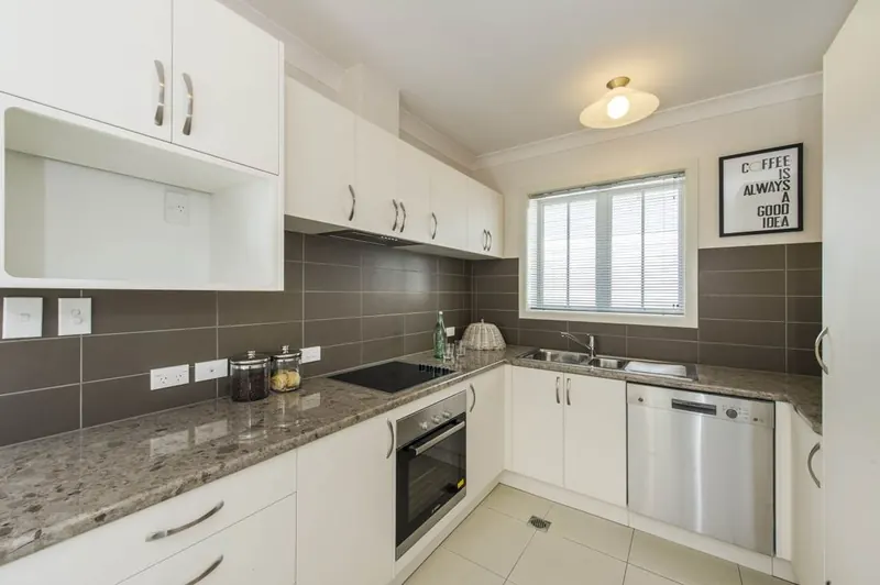 Renovated kitchen with white cabinets and stone benchtop